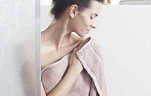 Žena při osušování pokožky po sprchování