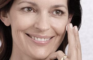 Žena aplikující krém na obličej.
