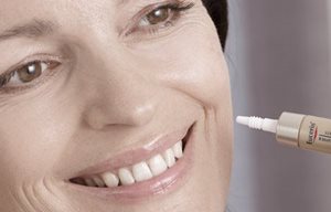 Žena aplikující krém Eucerin na levou tvář.