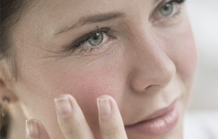 Žena se rukou dotýká obličeje