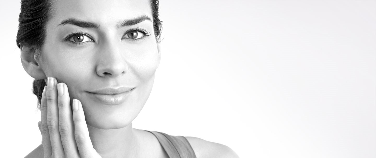 Žena ve středních letech se rukou dotýká pravé tváře 