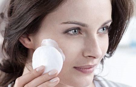 Žena při čištění pleti odličovacím tamponem